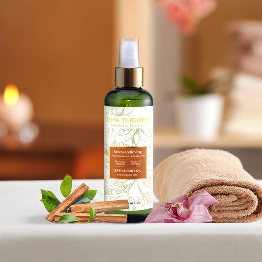 A bottle of stress-relieving bath and body oil on a spa table with cinnamon sticks, green leaves, a rolled towel, and an orchid