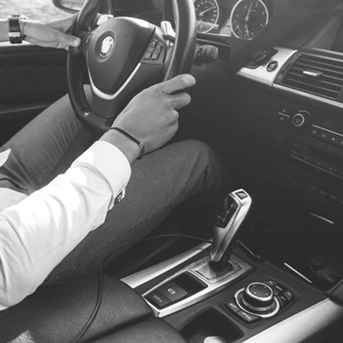 Interior of a car featuring the driver's hands on the steering wheel, conveying sophistication and control, with a car air freshener visible in the scene.